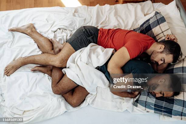 gay couple sleeping together in bed in spooning position - romantic young couple sleeping in bed stock pictures, royalty-free photos & images