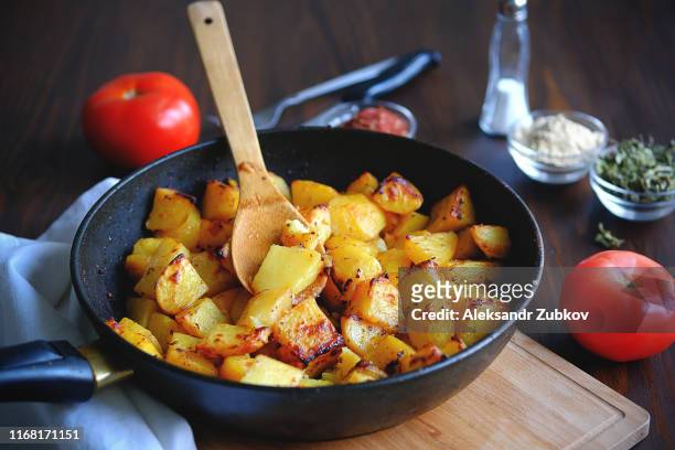 baked in the oven potatoes with spices in a pan on a wooden table. the concept of delicious and healthy home-cooked food. rustic style. organic vegetables, vegan and vegetarian recipe. - prepared potato stock pictures, royalty-free photos & images