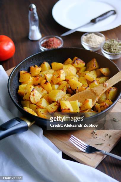 baked in the oven potatoes with spices in a pan on a wooden table. the concept of delicious and healthy home-cooked food. rustic style. organic vegetables, vegan and vegetarian recipe. - american potato farm stockfoto's en -beelden