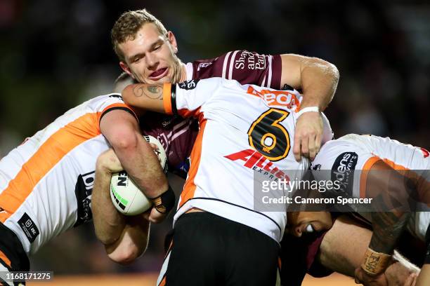 Tom Trbojevic of the Sea Eagles is tackled during the round 22 NRL match between the Manly Sea Eagles and the Wests Tigers at Lottoland on August 15,...