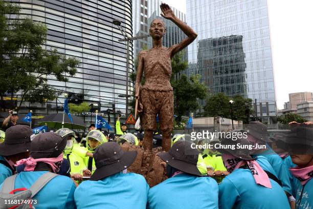 South Korean protesters push a statue symbolizing Korean laborers forcibly taken abroad by the imperialist Japan during World War II, to enter into...