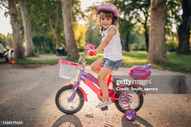 cute little girl riding bicycle in park - pink hard hat stock pictures, royalty-free photos & images