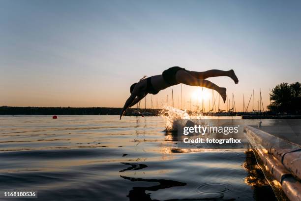 zomerdag: jonge vrouw sprong van de steiger naar het meer tijdens zonsondergang - land-brandenburg stockfoto's en -beelden