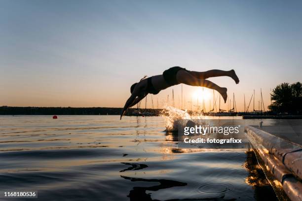 夏日：年輕女子從碼頭跳入湖中，而日落 - taking the plunge 個照片及圖片檔