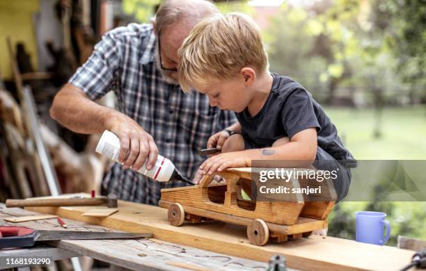 grootvader en kleinzoon maken van een auto van hout - klussen stockfoto's en -beelden