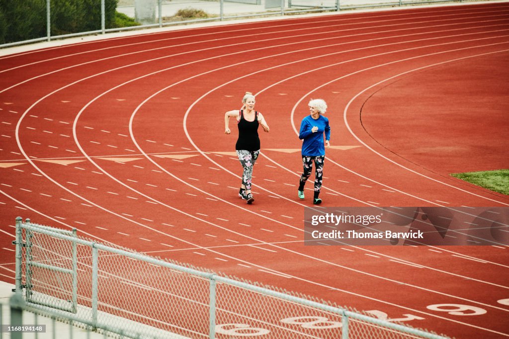 Smiling senior female athletes racewalking on track