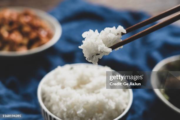 hand taking some white rice with chopsticks - stäbchen stock-fotos und bilder