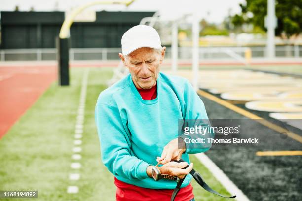 Senior male track athlete putting on fitness watch before working out