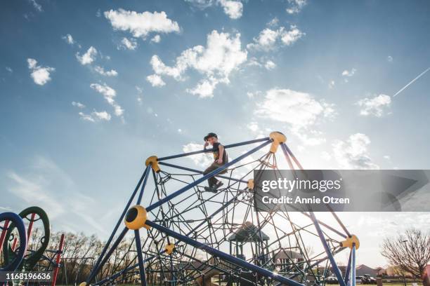 boy at the top of playground jungle gym - speeltuintoestellen stockfoto's en -beelden