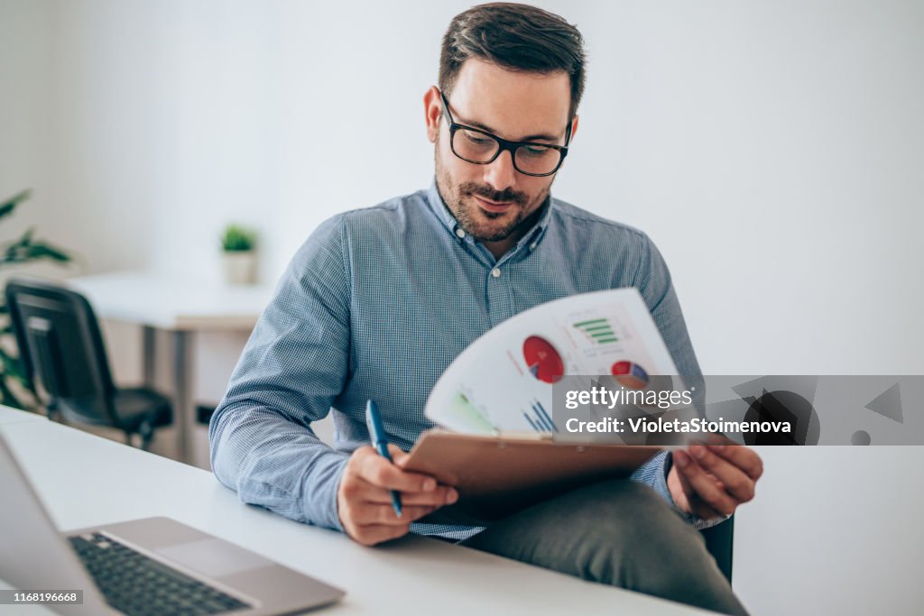 Businessman reading document at desk in office