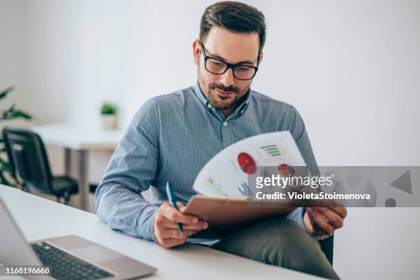 businessman reading document at desk in office - man with clipboard imagens e fotografias de stock