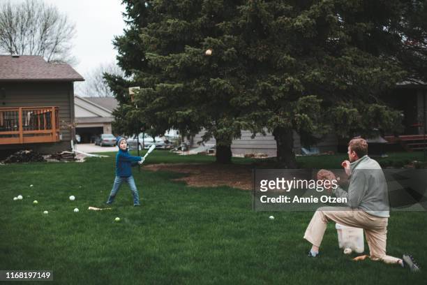 father and son practicing baseball - backyard baseball stockfoto's en -beelden