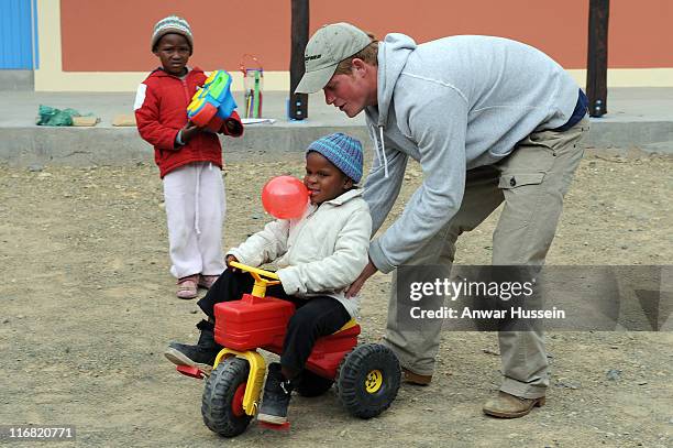 Prince Harry pushes a child on a toy tractor at the Lesotho Child Counselling Unit on July 9, 2008 in Maseru, Lesotho. The Prince's charity Sentebale...