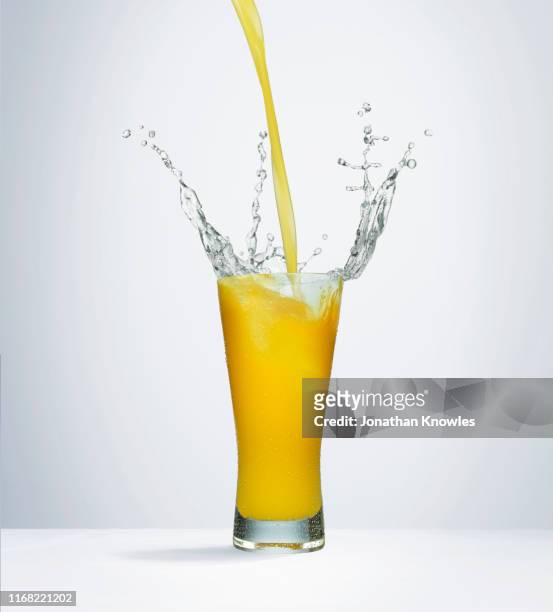 splashing orange juice - splash jus d'orange stockfoto's en -beelden