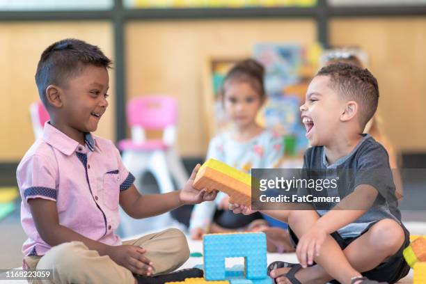 happy preschool students playing together in classroom - sharing stock pictures, royalty-free photos & images