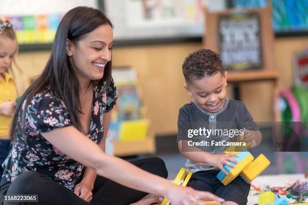 preschool students playing in classroom with teacher - development camp stock pictures, royalty-free photos & images