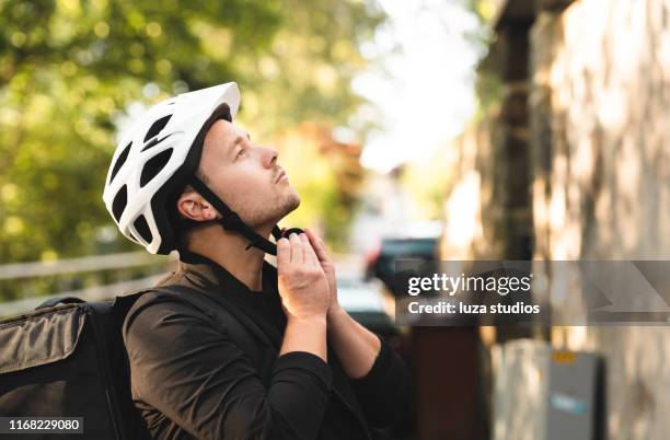 young man delivering food by bike in the city - sports helmet stock pictures, royalty-free photos & images