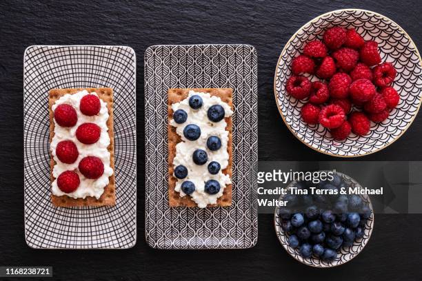 various crispbread biscuits with cream cheese and fruits. blueberries, raspberries and grapes. - rectangle photos et images de collection