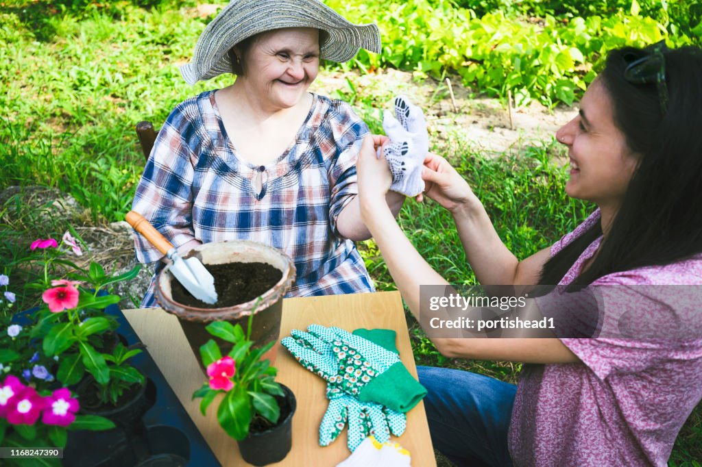 Woman with Down Syndrome and her relative planting flowers together. Gardening.