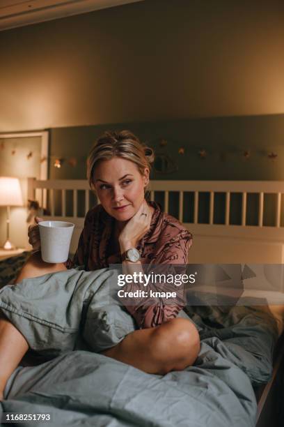 vera donna in pigiama rilassante in camera da letto con tè - pigiama foto e immagini stock