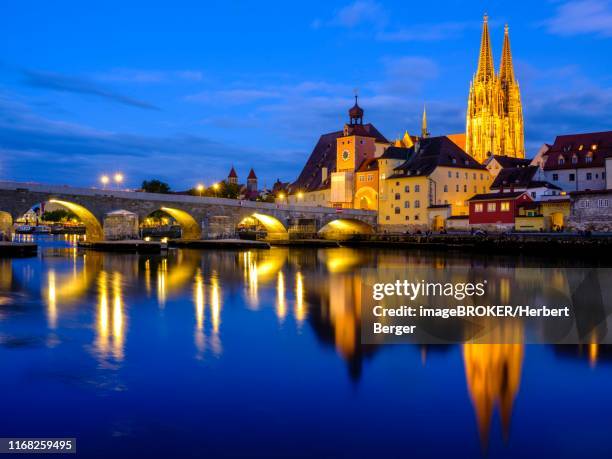 illuminated old town with stone bridge and cathedral reflected in the danube at dusk, regensburg, upper palatinate, bavaria, germany - regensburg stock-fotos und bilder