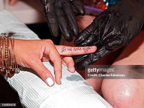 Singer/songwriter Aubrey O'Day's finger is tattooed by tattoo artist Friday Jones during the opening of Friday Jones Fifth Ave. Tattoo Studio at...