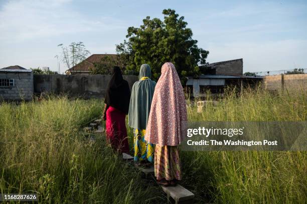 Three young girls, including Fatima and Goggo, walk home in Maiduguri, Nigeria, on September 4, 2019. Fatima spent 15 months in the Giwa barracks...