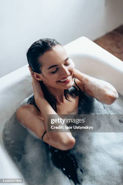 young beautiful woman relaxing in bubble bath - woman bath tub wet hair stock pictures, royalty-free photos & images