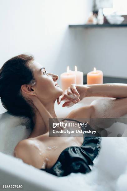 young beautiful woman relaxing in bubble bath - woman bath tub wet hair stock pictures, royalty-free photos & images