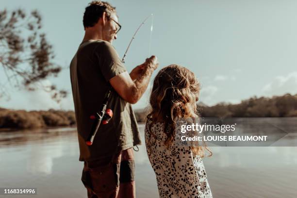 dad fixes fishing rod for his daughter - fischen stock-fotos und bilder