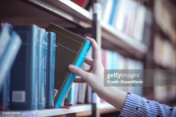 hand of woman selecting a book from book shelf - choosing a book stock pictures, royalty-free photos & images