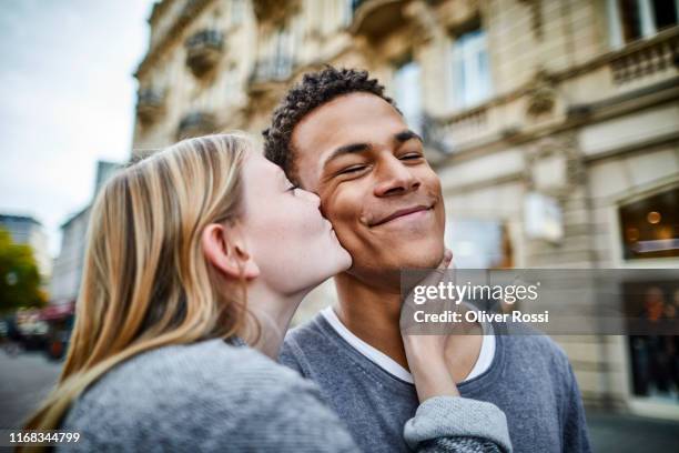 young woman kissing boyfriend in the city - young couple kiss ストックフォトと画像