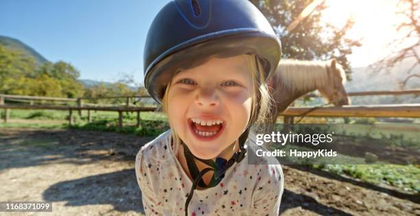 smiling little girl standing on ranch - riding hat stock pictures, royalty-free photos & images