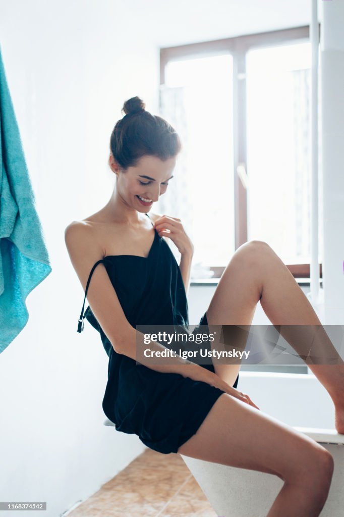 Young woman woman feeling her smooth legs in the bathroom at home