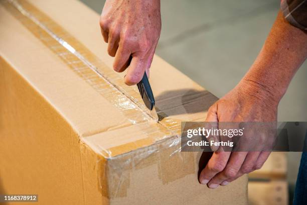 een industrieel werkplek magazijn veiligheid onderwerp. een vrouwtje snijden een doos met behulp van een utility mes. - utility knife stockfoto's en -beelden