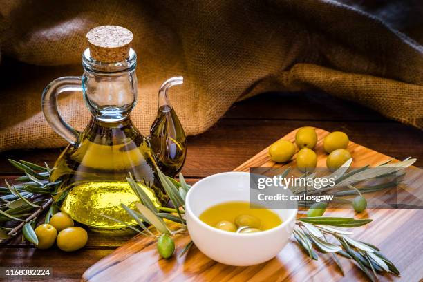 オリーブの木製のまな板にオリーブの枝が付いているオリーブオイルのびん - olive oil ストックフォトと画像