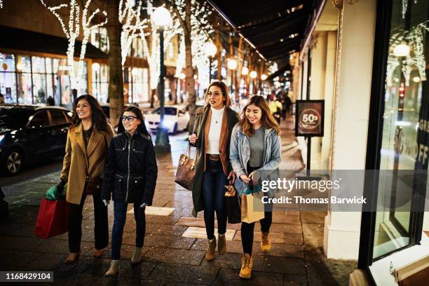 two mature women and teenage daughters walking on sidewalk on winter evening while shopping during holidays - mother with daughters 12 16 stock pictures, royalty-free photos & images
