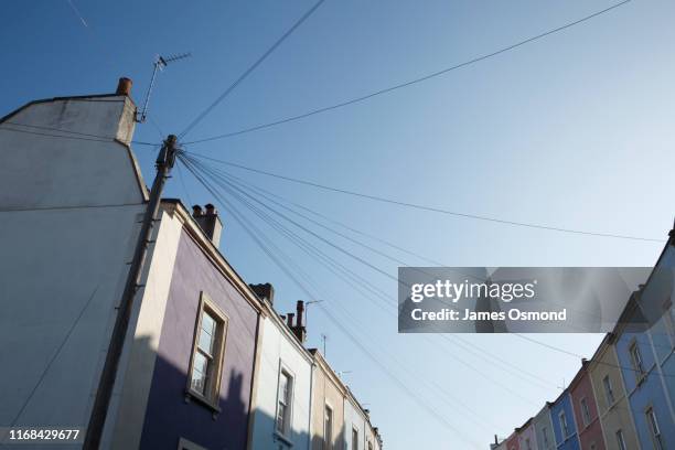 telegraph pole and wires connected to a multicolour row of terraced houses. - telephone line stock pictures, royalty-free photos & images