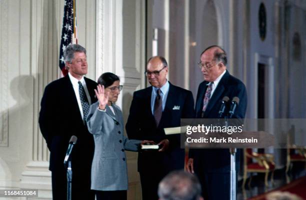 Ruth Bader Ginsburg holds her right hand up as Chief Justice William H Rehnquist administers the oath of office as she is sworn in as Associate...