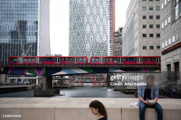 General view of a person eating lunch in Canary Wharf as a Docklands Light Railway train passes by on August 06, 2019 in London, England.