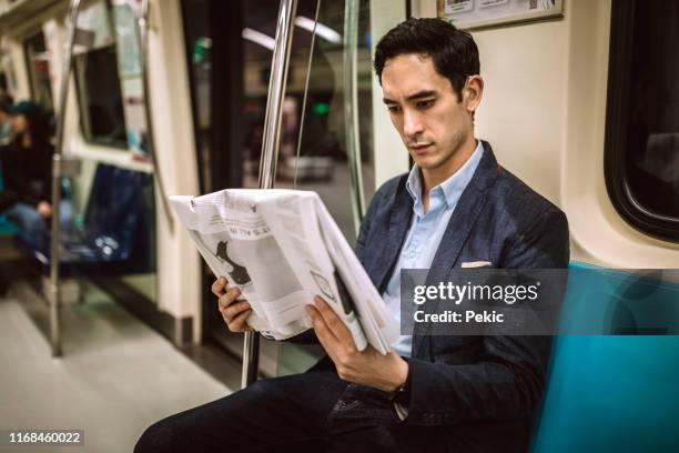 reading news on his way to work place in subway - reading newspaper stock pictures, royalty-free photos & images