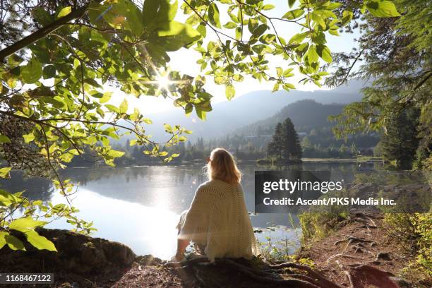 woman relaxes on mountain lakeshore at sunrise - person escaping stock pictures, royalty-free photos & images