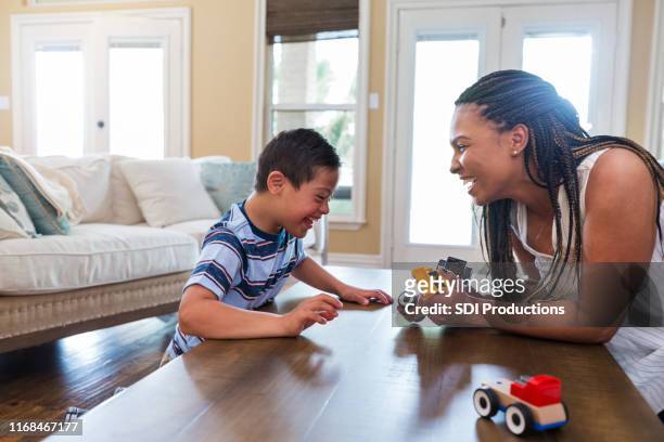 mid adult therapist uses play therapy with young boy - special needs children stock pictures, royalty-free photos & images
