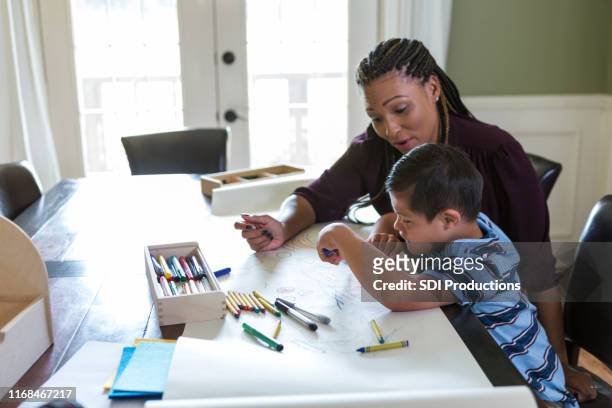 mid adult therapist works with young boy at home - alternative therapy stock pictures, royalty-free photos & images