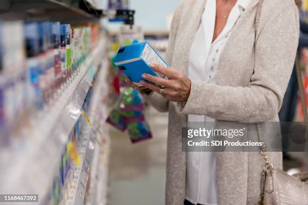 mujer irreconocible se encuentra en la farmacia de la tienda tomando la decisión - medicina para los resfriados fotografías e imágenes de stock