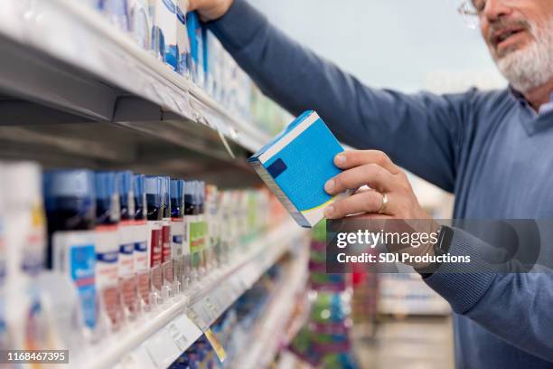 unreconocible hombre maduro lee las instrucciones de los medicamentos en la farmacia - medicina para los resfriados fotografías e imágenes de stock