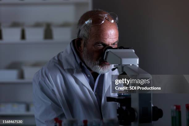 male scientist looks into microscope - lab night stock pictures, royalty-free photos & images