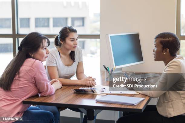 loan officer talks with hispanic mother and daughter - women talking in a bank with computer stock pictures, royalty-free photos & images