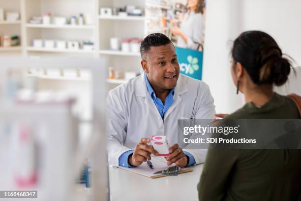 pharmacist explains side effects of generic drug to unrecognizable customer - black pharmacist stock pictures, royalty-free photos & images