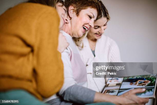 mother and daughters going through photo album - three people in bed stock pictures, royalty-free photos & images